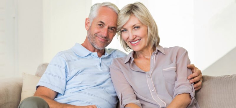 Mature man and woman sitting on couch together and smiling