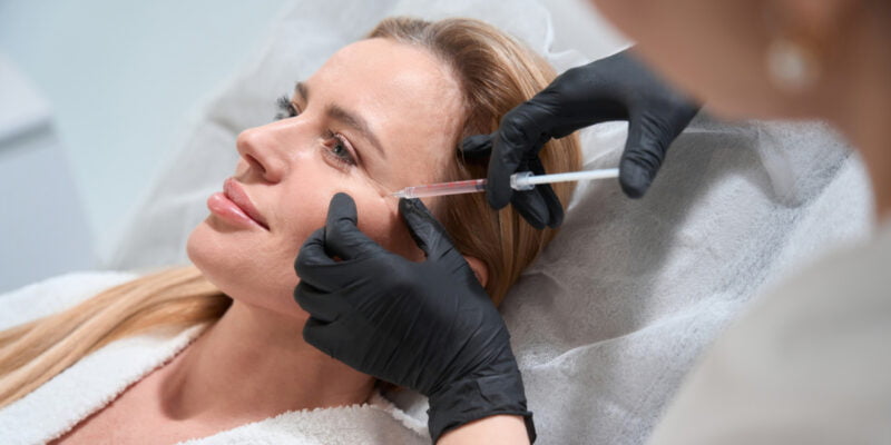 Woman getting a cheek filler administered by an injector at a med spa