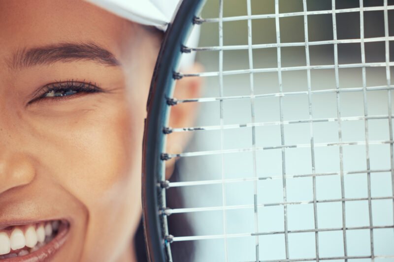 Close up of woman holding a tennis racket and smiling