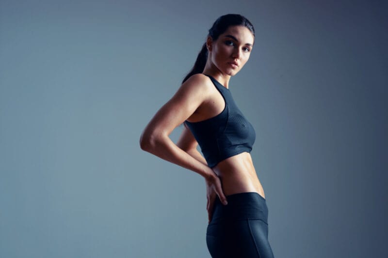 Fit woman in athletic clothing against dark blue background